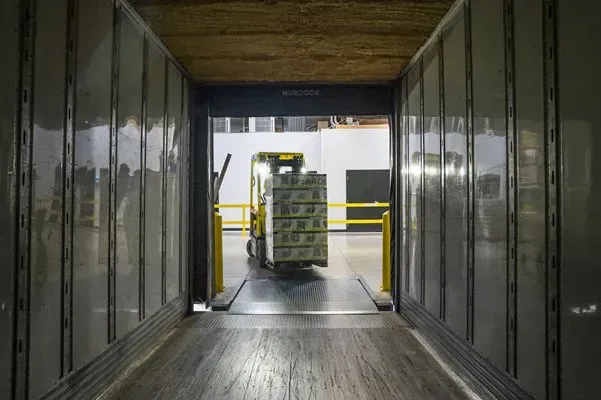 Forklift loading palletized goods into a truck trailer