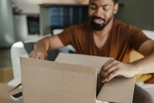 Person packing items into a cardboard shipping box