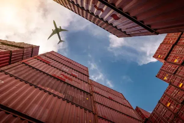 Aircraft flying above stacks of shipping containers