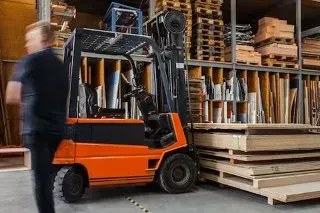 Forklift beside stacked timber and pallets in a warehouse