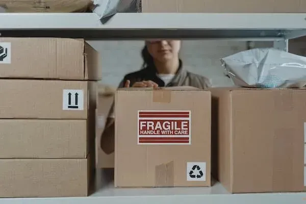 Worker handling a box marked Fragile on a storage shelf