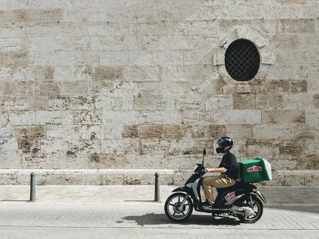 Delivery rider transporting a parcel by scooter