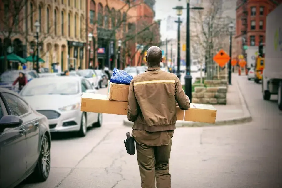 Courier carrying several parcels along a city street