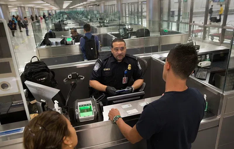 Border officer checking a traveller's documents at an airport inspection desk